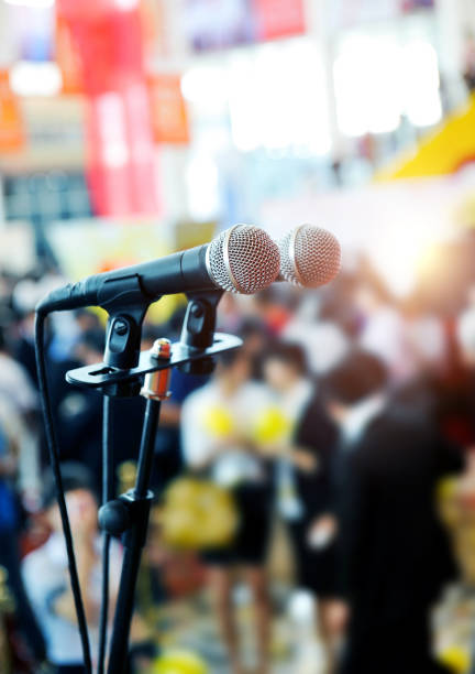 istock Closeup microphone in auditorium with blurred people in the background 1924375482