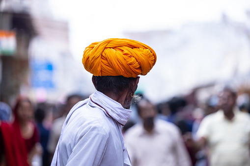 Pushkar, Rajasthan, India - November 2022: Pushkar fair, Portrait of an rajasthani old male with in white traditional dress and colorful turban at pushkar fair ground.