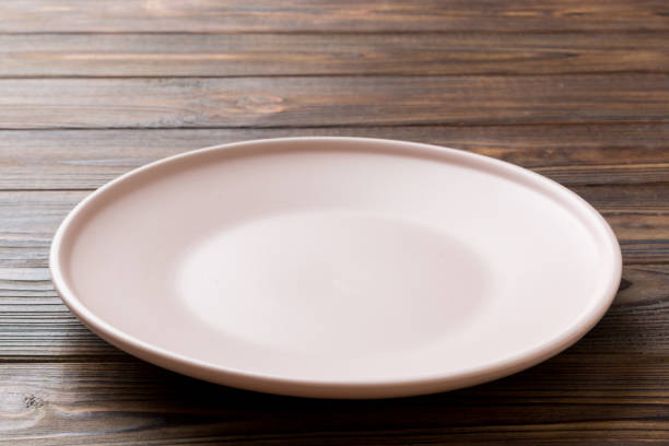 istock Perspective view of empty pink plate on wooden background. Empty space for your design 1924386840