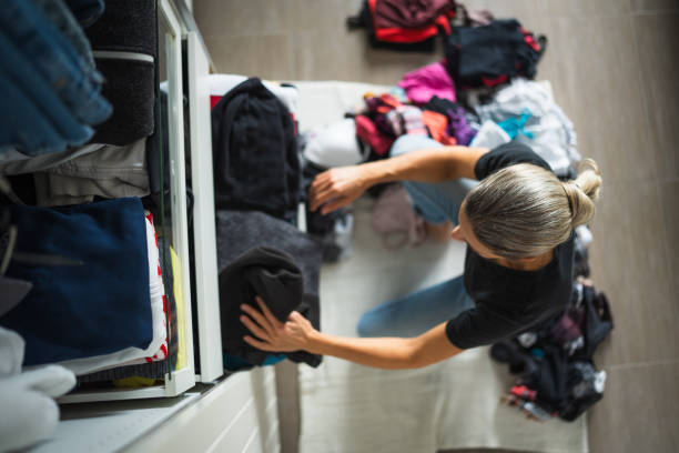 view from above at woman sorting clothes at home at open wardrobe