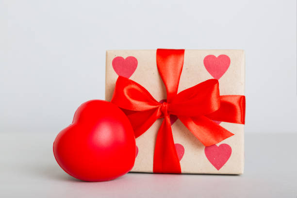 istock gift box with red bow and red heart on colored background. Perspective view. Flat lay 1924387107