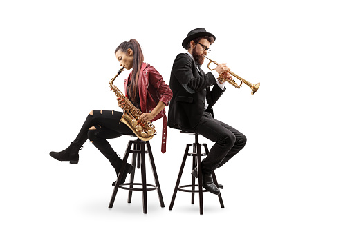 Male and female musicians sitting on chairs and playing a sax and a trumpet isolated on white background
