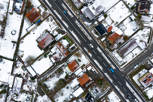Drone point of view in season winter snow covered detached one family houses in Odense. Residential district with road crossing through