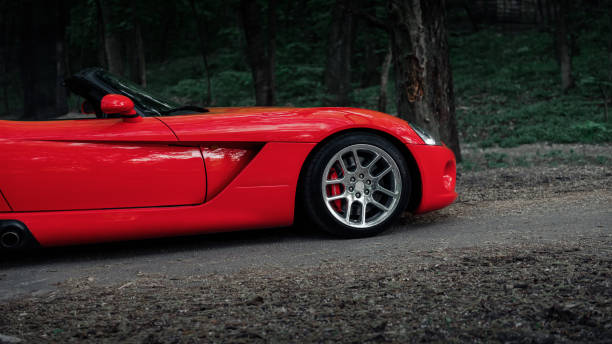 Kyiv, Ukraine - April 30 2018: Front part side view of american roadster sports car. Car is located on a narrow asphalt road through woodlands.
