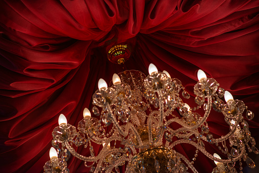 Bohemian crystal chandelier with red satin fabric ceiling drape.