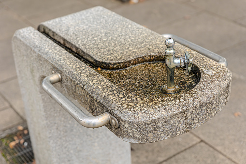 Outdoor drinking fountain made of stone with a silver tap
