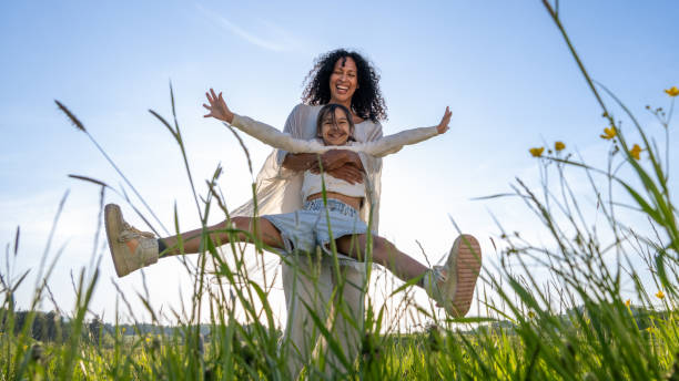 Woman spinning her daughter in meadow