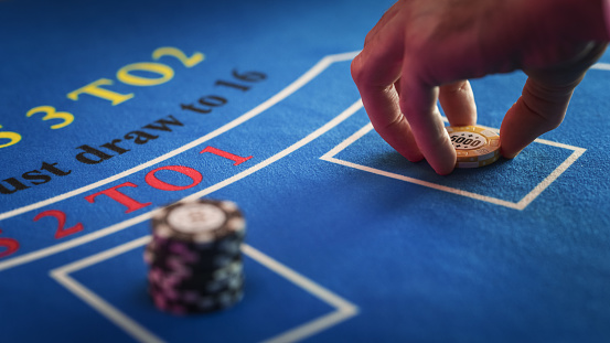 Close Up on Casino Baccarat Gambling Table: Anonymous Croupier Dealing Playing Cards on a Blackjack Table with Bet Chips in Place. Poker Chips are Being Exchanged as the Lucky Guest Wins the Jackpot