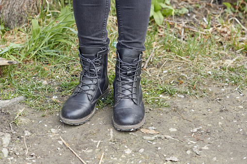 A girl in black winter boots is standing on the ground