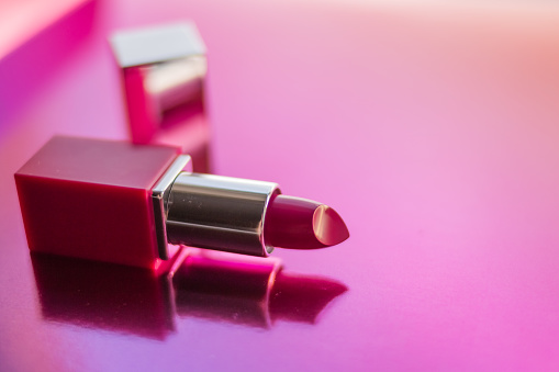 Pink lipstick open on the background close up