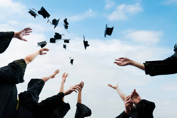 istock Graduating students hands throwing graduation caps in the air 1924478126