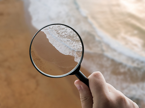 A magnifying glass focusing on a sand beach