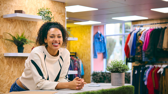 Portrait Of Smiling Female Sales Assistant At Cash Desk In Pop Up Fashion Or Clothes Store