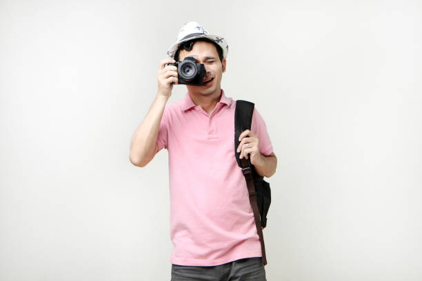 Asian man backpacker taking photo with digital camera. travelling concept. on isolated background