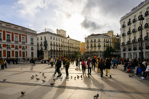 Madrid, Spain - Oct 27, 2023: Locals and tourists walk among the pigeons on Puerta del Sol square.