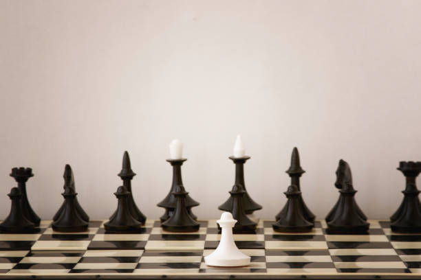 jeden biały pionek przeciwko pełnemu zestawowi czarnych figur szachowych. nierównowaga sił przed bitwą, nierówne siły do walki - imbalance chess fighting conflict zdjęcia i obrazy z banku zdjęć
