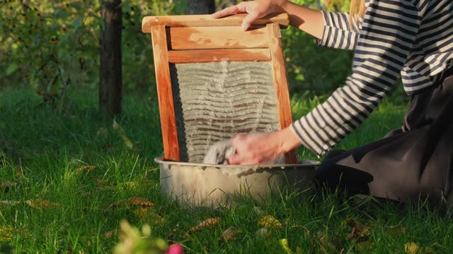 Woman washing on old retro washboard. Washing clothes the old fashion way is a way of life. Washerwoman doing laundry by hand. Antique Washboard
