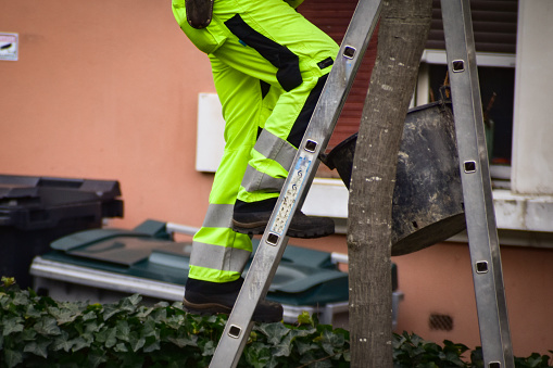A city worker or construction worker is climbing a ladder to do his job