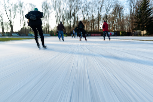 Doorn, Netherlands - 01/11/2024: People ice-skating on a cold sunny morning on a track in Doorn, Motion-blur