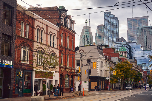 Toronto, Canada; 11th of October, 2023. The old houses  in Queen street make contrast with the skyscrapers in Toronto. Warm colors for the old houses and cold colors for the skyscrapers