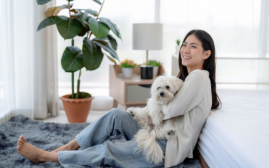 Happy Asian woman relaxing at home with her pet.