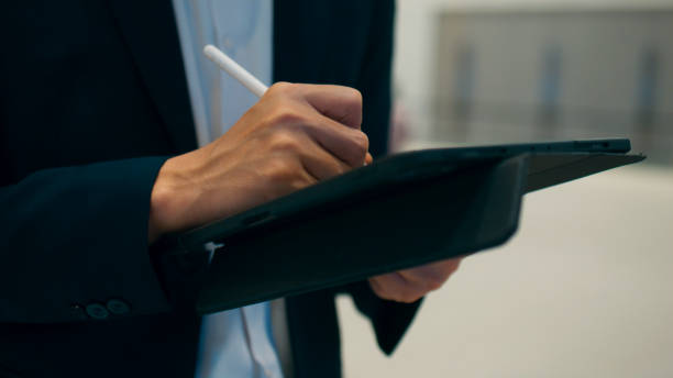 istock Smart young Asian businessman CEO wearing business suit using digital tablet, working, writing on note pad and standing in office, Professional executive manager working on tech device 1924759929