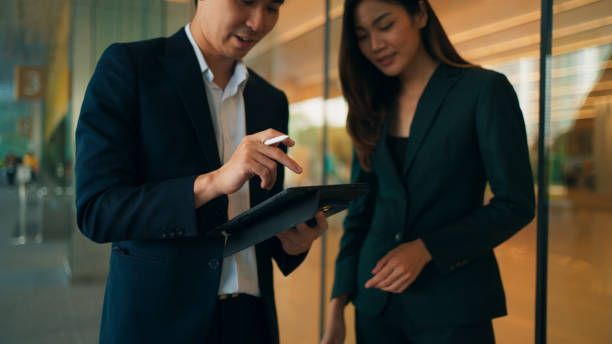 istock Two happy professional young Asian business people team using digital tablet, working together, meeting and discussing financial market plan in modern office building 1924764274