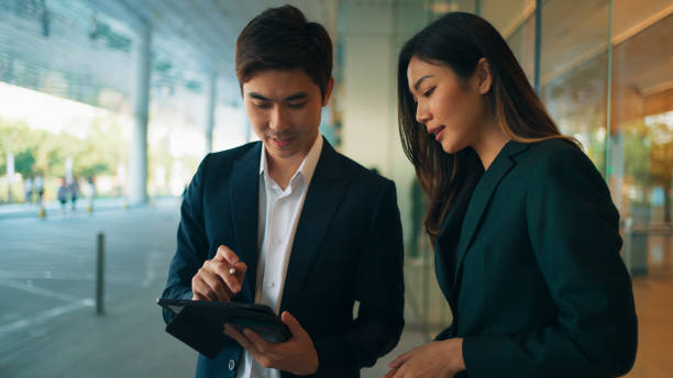 istock Two happy professional young Asian business people team using digital tablet, working together, meeting and discussing financial market plan in modern office building 1924764287