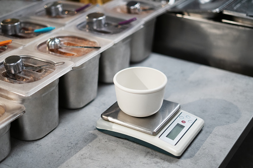 Weighing ingredients in the restaurant. Small measuring bowl on the scales.