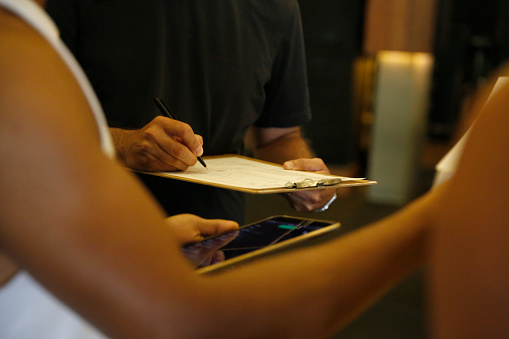 Close-up shot of unrecognizable man filling in questionaire before training at gym