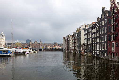 Amsterdam, Netherlands - April 21, 2023: A general view of Central Station and the canal cruises pier at the Damrak canal downtown Amsterdam.