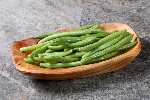 Green beans in white bowl on cutting board. Top view. Copy space.