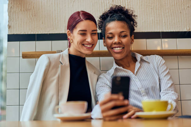 istock Two female friends sitting at the cafe, using a mobile phone, drinking coffee. 1924790102