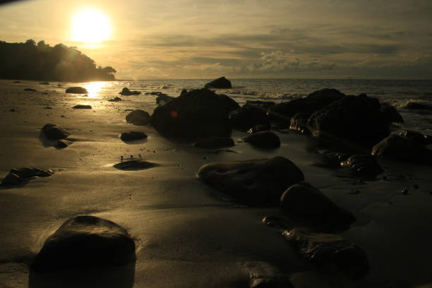 Beautiful late afternoon sunset at the beach, silhouette of rocks on the beach.