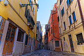 Scenic view of narrow alley with historic houses at Italian City of Venice on a summer day.