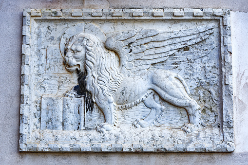Close-up of winged lion with book at facade of historic building at the old town of Venice on a summer day. Photo taken August 6th, 2023, Venice, Italy.