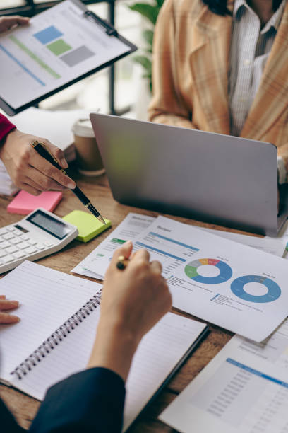 istock Business team Two managers work on accounting documents and the team works together to give presentations and help solve problems with accounting documents. Close-up vertical image 1924808066