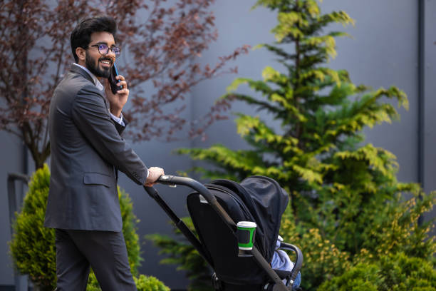 istock Smiling young businessman talking on the phone while having a walk with his kid 1924833871