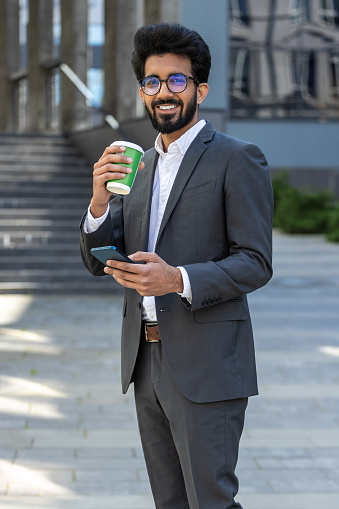 Elegant young businessman having coffee break and looking contented