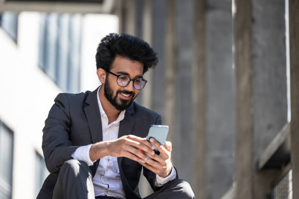 istock Dark-haired hindu man sitting on the steps with a phone in hands 1924837180