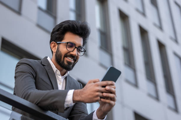 istock Smiling good-looking hindu man texting on the phone and feeling contented 1924837727