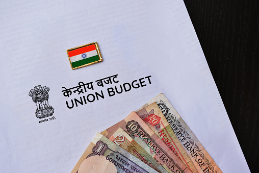 Indian Union budget concept with currency notes placed along with Indian flag over white background.