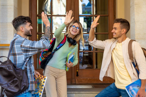 istock Young happy students having fun together outside university giving high five. 1924870684
