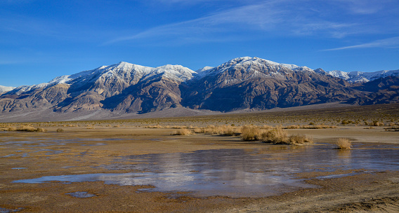 Salt flats in Badwater Basin in Death Valley national park , California during sunset with majestic mountains.