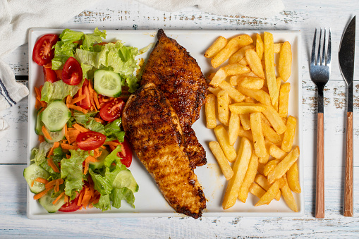 Grilled chicken. Grilled chicken breast with salad and fries on a white background