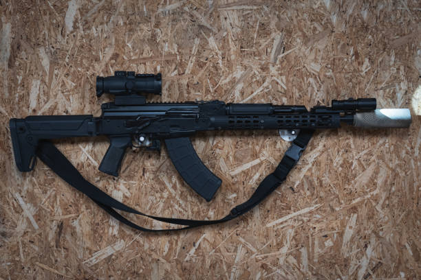 istock An AKM tactical rifle with a silencer, a weapon flashlight and a prismatic sight hangs on the wall in a shooting range. 1924915110