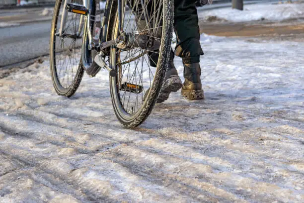 person pushes bicycle on icy surface