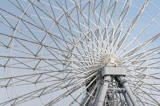 A giant ferris wheel pillar structure with blye sky in daytime as background. Close-up and selective focus.