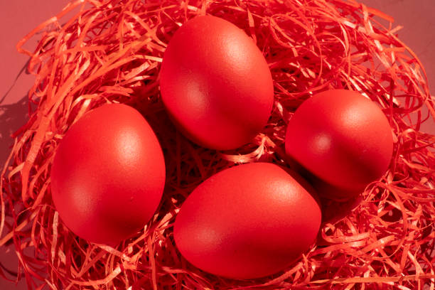 Colored eggs symbolize Easter in shades of red on straw