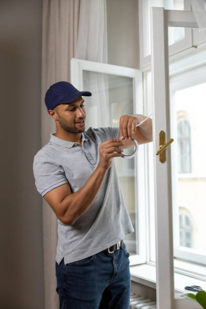 istock Young man putting sealing tape on window in house. 1924942092